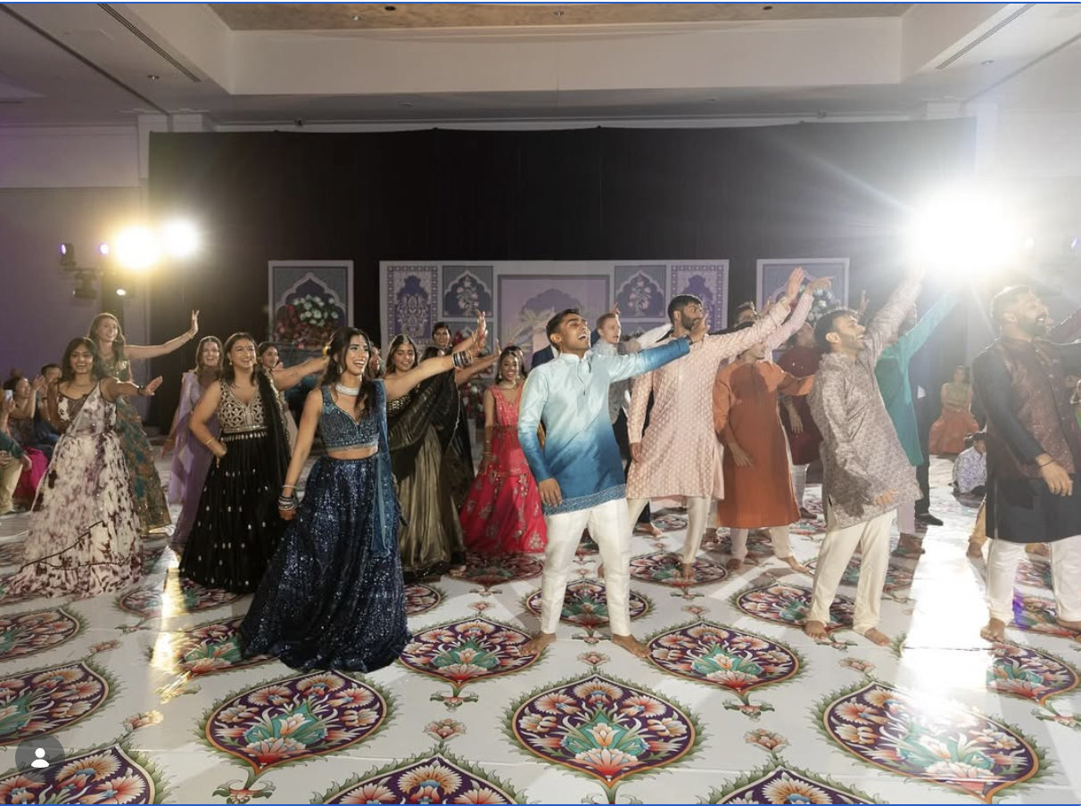 Wedding party performing a group sangeet routine on a decorated dance floor
